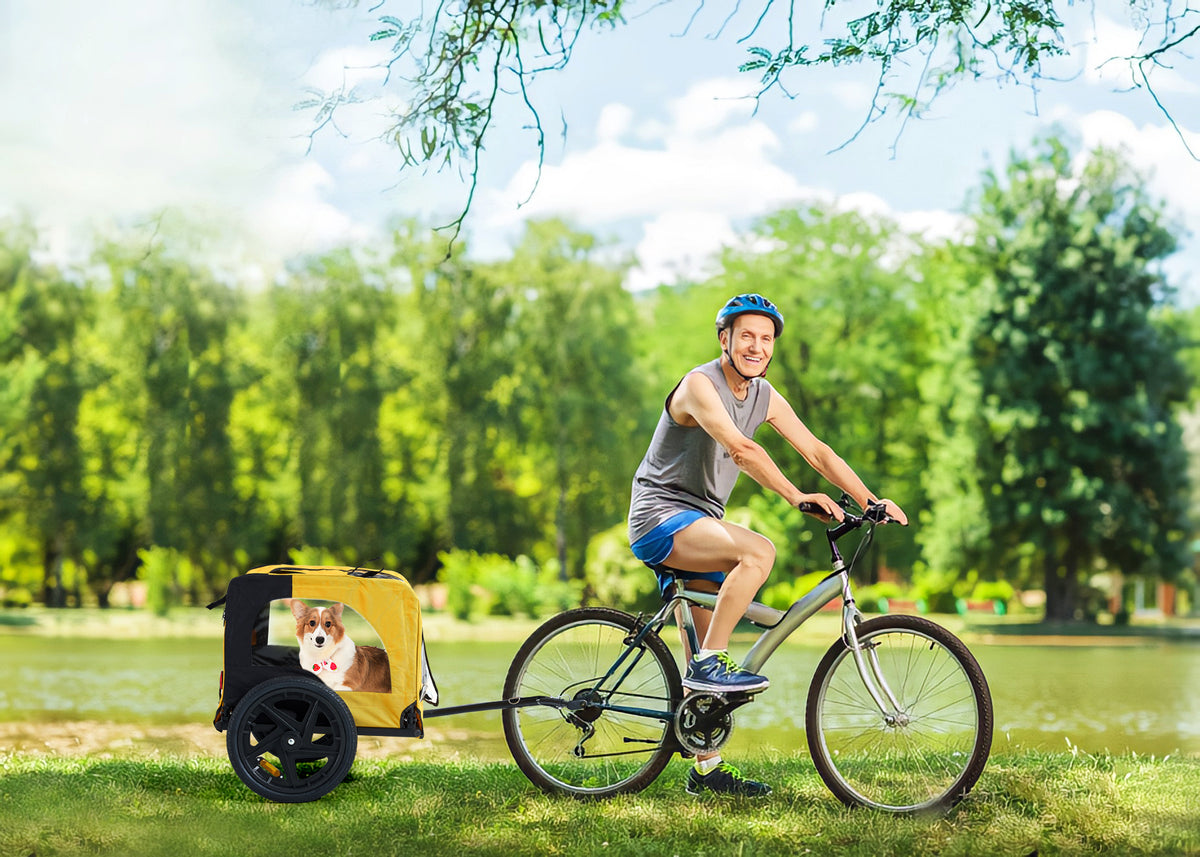 Dog riding inside yellow foldable bike trailer